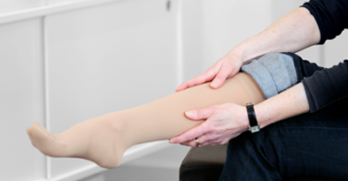 Kvinde tager kompressionsstrømpe på - Sahva