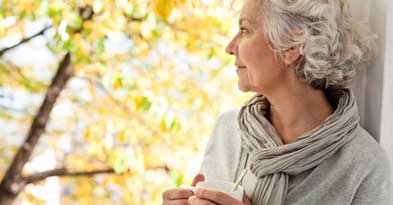 Kvinde kigger ud af vinduet med en kop te i hånden - Sahva