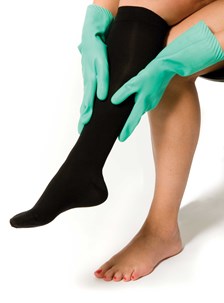 Kvinde tager kompresseionsstrømper på med gummihandsker